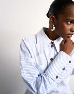 Model wearing Tolu Coker x Topshop stripe long sleeve shirt in blue stripe