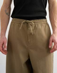 Model wearing Baggy fit herringbone trousers in khaki