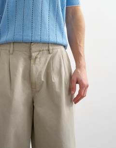 Model wearing Baggy fit trousers with pleats in stone