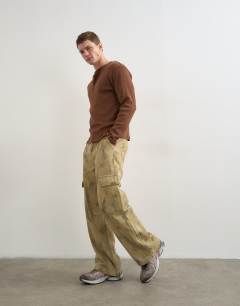 Model wearing Baggy fit twill camo print trousers in khaki