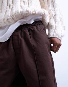 Model wearing Baggy  trousers in twill with pintuck in brown