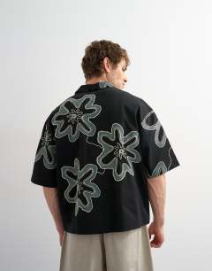 Model wearing Boxy fit heavyweight jersey shirt with all over floral applique in black