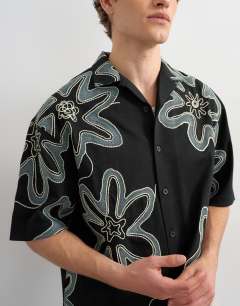 Model wearing Boxy fit heavyweight jersey shirt with all over floral applique in black