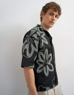 Model wearing Boxy fit heavyweight jersey shirt with all over floral applique in black