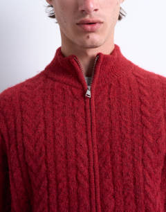 Model wearing Cable knitted zip through funnel neck cardigan in red