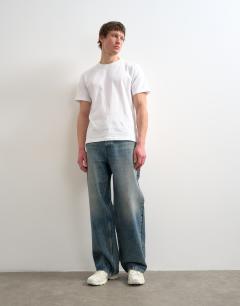 Model wearing Circular design rigid baggy jean in mid wash tint