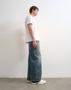 Model wearing Circular design rigid baggy jean in mid wash tint