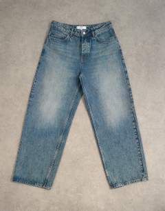 Model wearing Circular design rigid baggy jean in mid wash tint