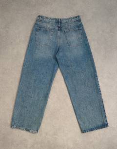 Model wearing Circular design rigid baggy jean in mid wash tint