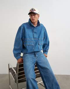 Model wearing Oversized fit denim jacket with funnel neck in mid wash