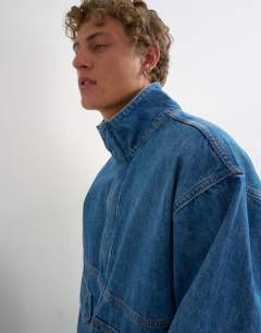 Model wearing Oversized fit denim jacket with funnel neck in mid wash