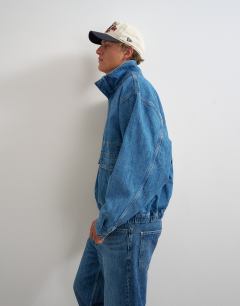 Model wearing Oversized fit denim jacket with funnel neck in mid wash