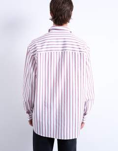 Model wearing Oversized fit long sleeve stripe shirt in burgundy