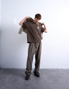 Model wearing Oversized Pegasus embroidered t-shirt with back text in brown
