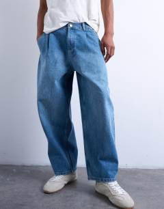 Model wearing Pleated barrel jean in mid wash blue