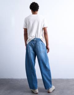 Model wearing Pleated barrel jean in mid wash blue