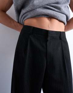 Model wearing Pleated wide leg trouser in black pinstripe