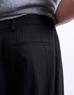 Model wearing Pleated wide leg trouser in black pinstripe