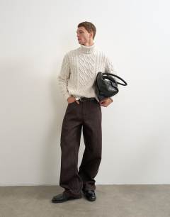 Model wearing Relaxed fit cable knitted roll neck jumper in ecru