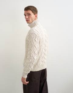 Model wearing Relaxed fit cable knitted roll neck jumper in ecru