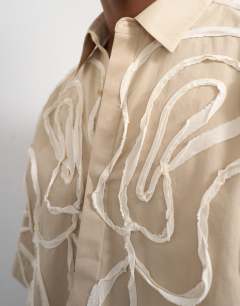 Model wearing Relaxed fit crop shirt with all over floral rope applique in stone