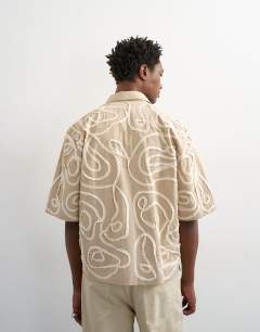 Model wearing Relaxed fit crop shirt with all over floral rope applique in stone