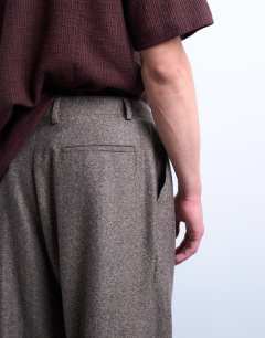 Model wearing Relaxed tapered pleated herringbone trouser in brown