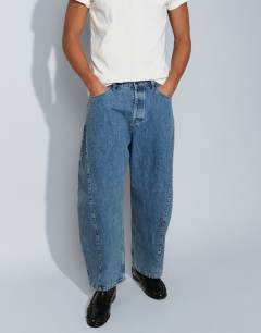 Model wearing Rigid barrel fit jean in mid wash