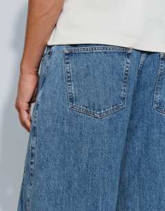 Model wearing Rigid barrel fit jean in mid wash