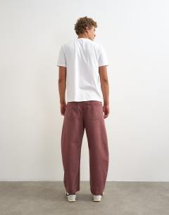 Model wearing Rigid barrel fit jean in washed burgundy