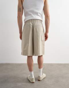 Model wearing Twill bermuda short with pronounced pleat in stone