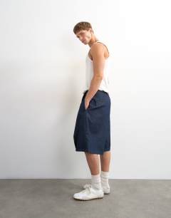 Model wearing Wide leg denim bermuda short with pronounced pleat in mid-wash blue
