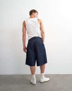 Model wearing Wide leg denim bermuda short with pronounced pleat in mid-wash blue