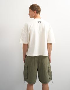 Model wearing X Jing boxy fit crop abstract breaking free graphic t-shirt with embroidery in ecru