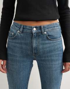 Model wearing 90's bootcut low rise jean in deep blue 
