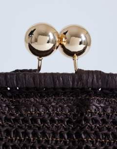 Model wearing Abbie medium woven clutch bag in chocolate