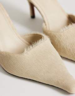 Model wearing Alfie real hair on leather pointed mid heeled mule court shoe in off white