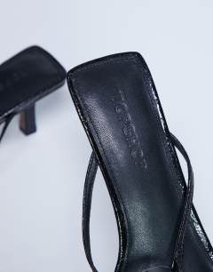 Model wearing Alice hardware square toe heeled mule in black