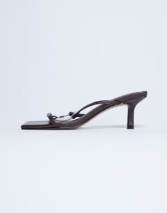 Model wearing Alice hardware square toe heeled mule in chocolate