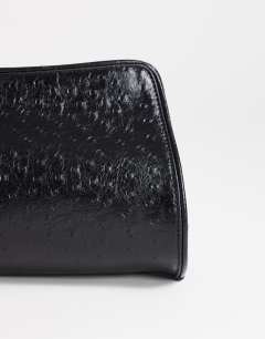 Model wearing Alice medium clutch bag in black ostrich