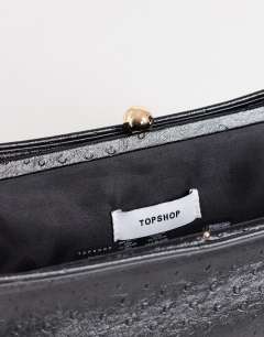 Model wearing Alice medium clutch bag in black ostrich