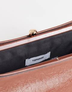 Model wearing Alice medium clutch bag in tan