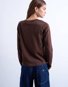 Model wearing Amico graphic boxy long sleeve tee in brown