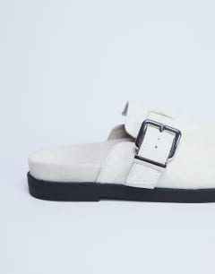 Model wearing Amy slip on mule with buckle in neutral hair on real leather