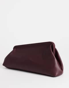 Model wearing Anna medium angular clutch bag in aubergine