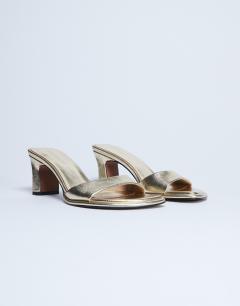 Model wearing Ari mule mid heeled sandal in gold