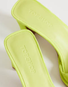 Model wearing Ari mule mid heeled sandal in lime