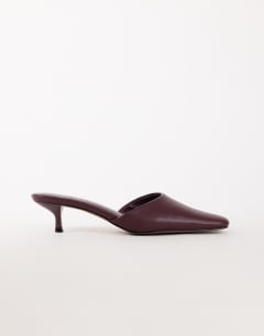 Model wearing Arthur rounded toe mid heel mule in aubergine