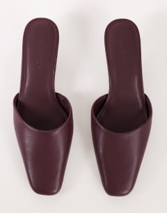 Model wearing Arthur rounded toe mid heel mule in aubergine