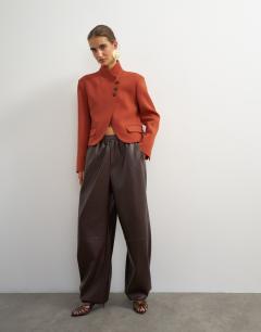 Model wearing Assymetric neck button detail blazer in rust